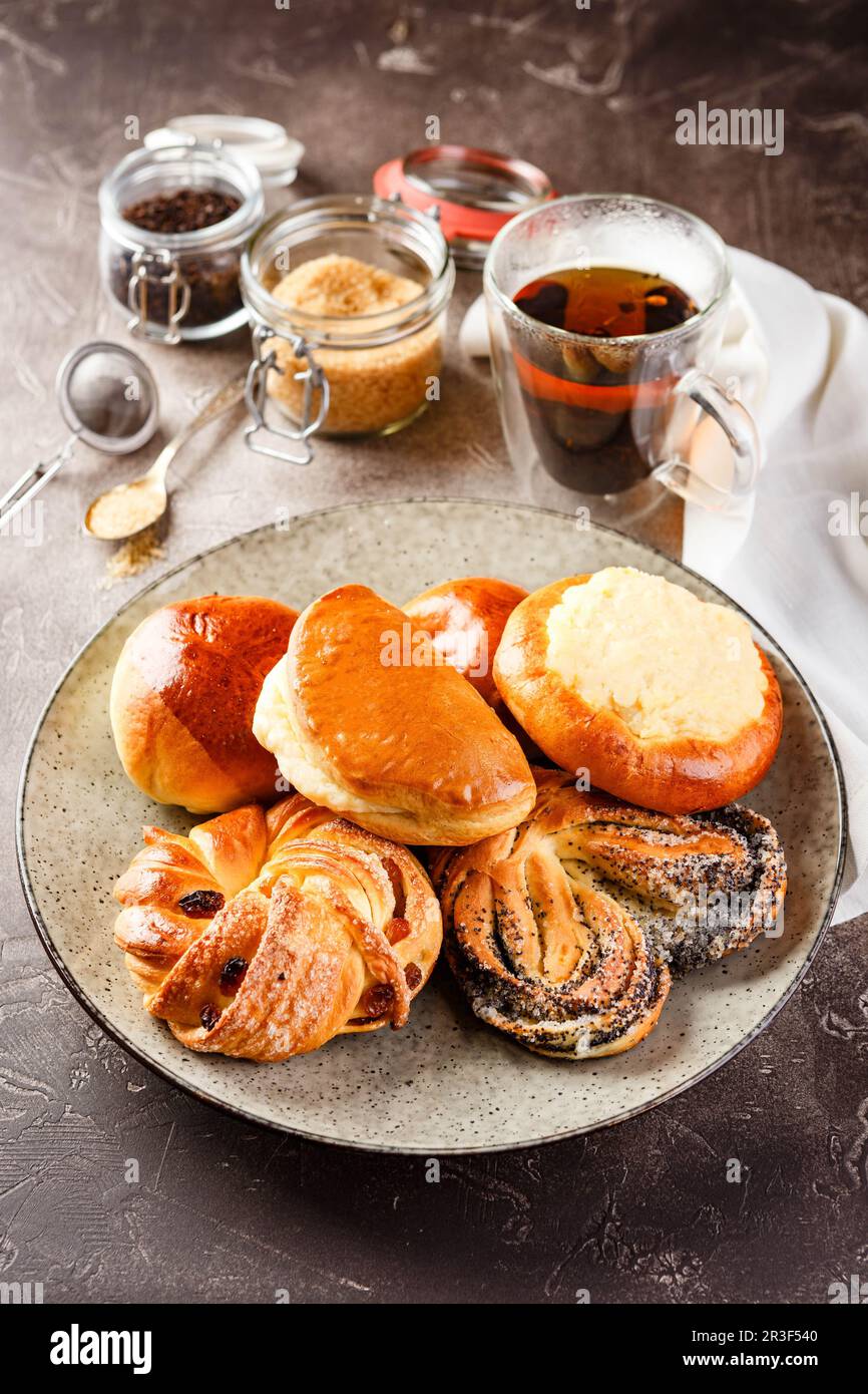 Torte di lievito dolce con diversi ripieni su piatto e bicchiere di tè Foto Stock
