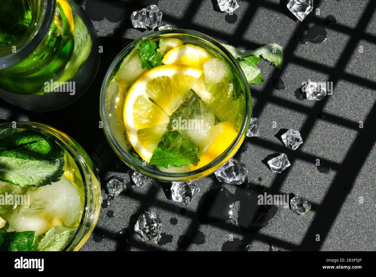 Mojito cocktail rinfrescante, bevande alcoliche. Limonata con foglie di limone e menta su fondo scuro. Trendy Shadow Ice cubes. Somma Foto Stock