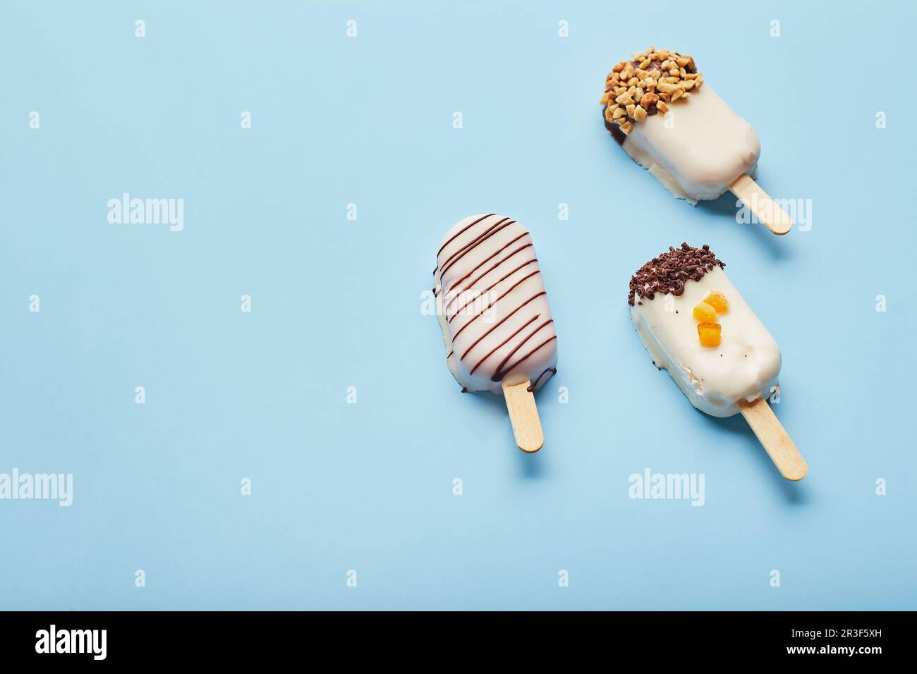 Dessert alla mousse con aromi di frutta sotto forma di gelato a forma di pop-sicle su sfondo blu. Foto Stock