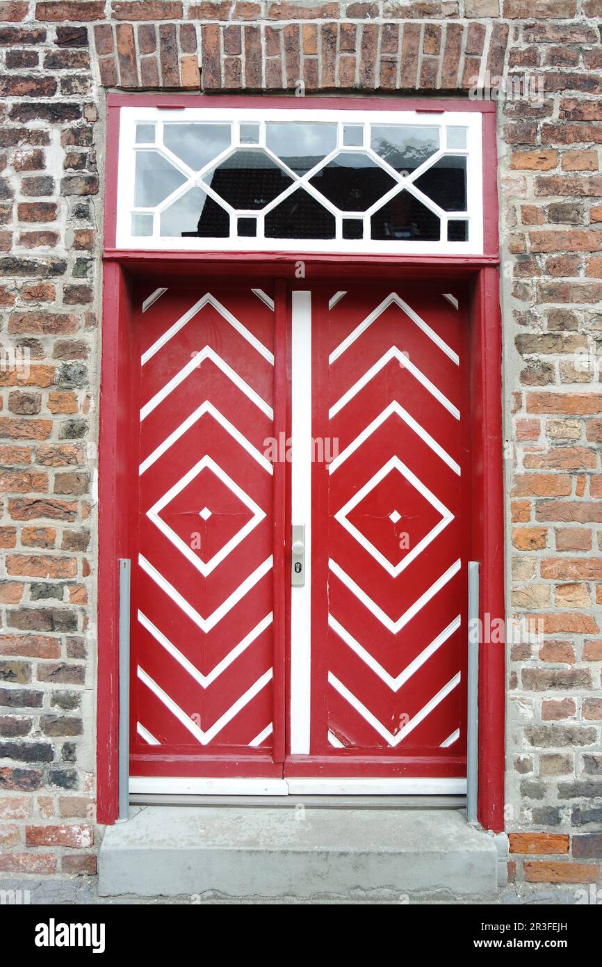 Vecchia porta di legno rosso in casa di mattoni Foto Stock