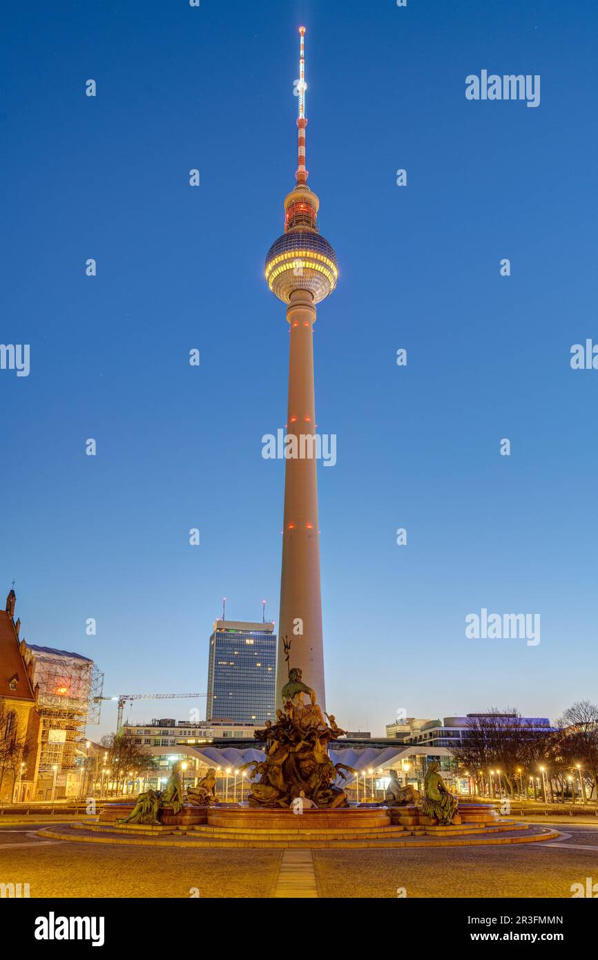 La famosa torre della televisione e la fontana Nettuno a Berlino a un'ora blu Foto Stock