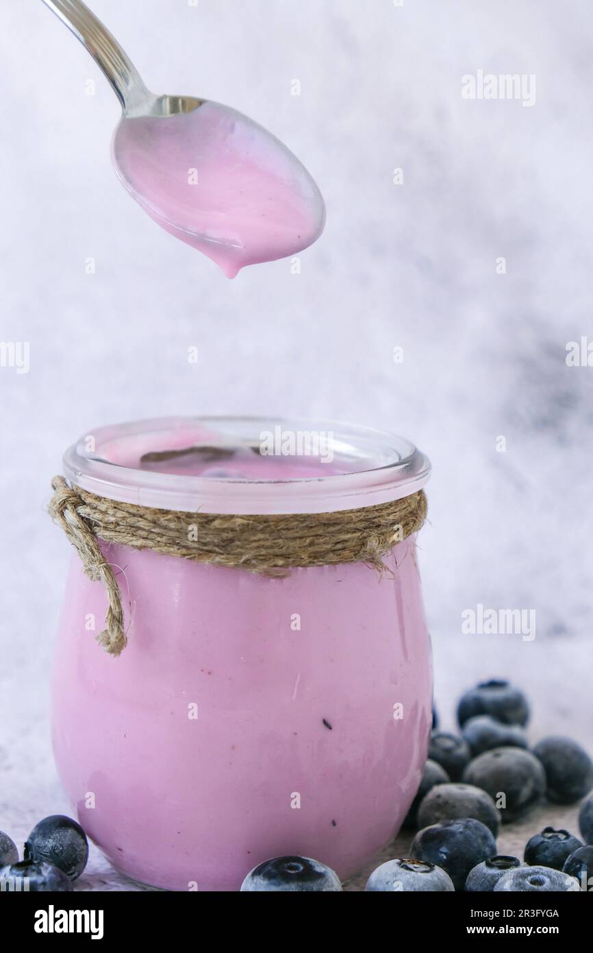 Ciotola con yogurt e mirtilli sul tavolo. Yogurt al mirtillo con mirtilli freschi. Colazione sana. Cibo super sano mangiare Foto Stock Ciotola con yogurt e mirtilli sul tavolo. Yogurt al mirtillo con mirtilli freschi. Colazione sana. Cibo super sano mangiare Foto Stock
