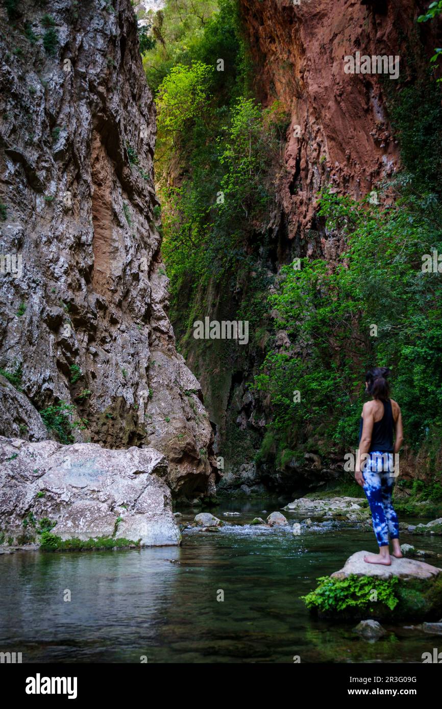 Donna che pratica yoga sul fiume, ponte di Dio, Akchour, Parco Naturale Talassettane, regione di Rif, marocco, africa. Foto Stock