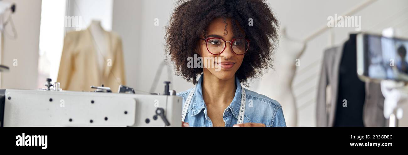 Il dressaker afroamericano tiene i video di ripresa del filo sul posto di lavoro in uno studio spazioso Foto Stock