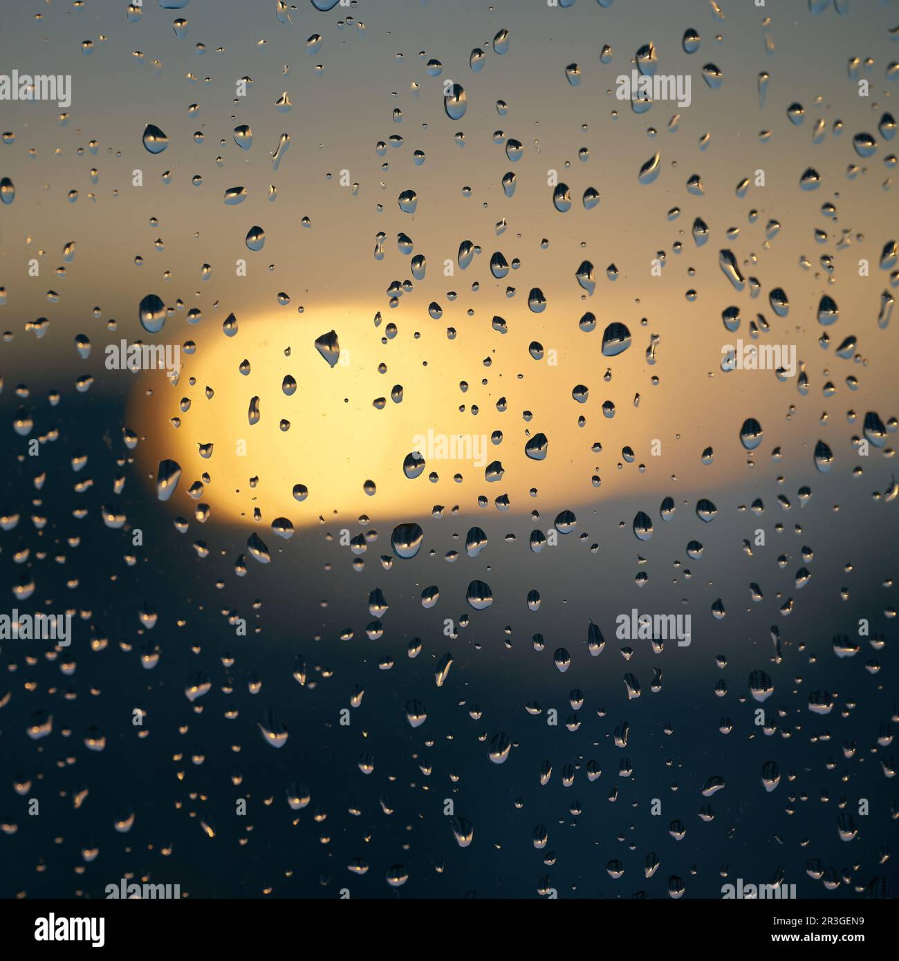 Gocce di pioggia sul vetro di una finestra dopo una pioggia al tramonto Foto Stock