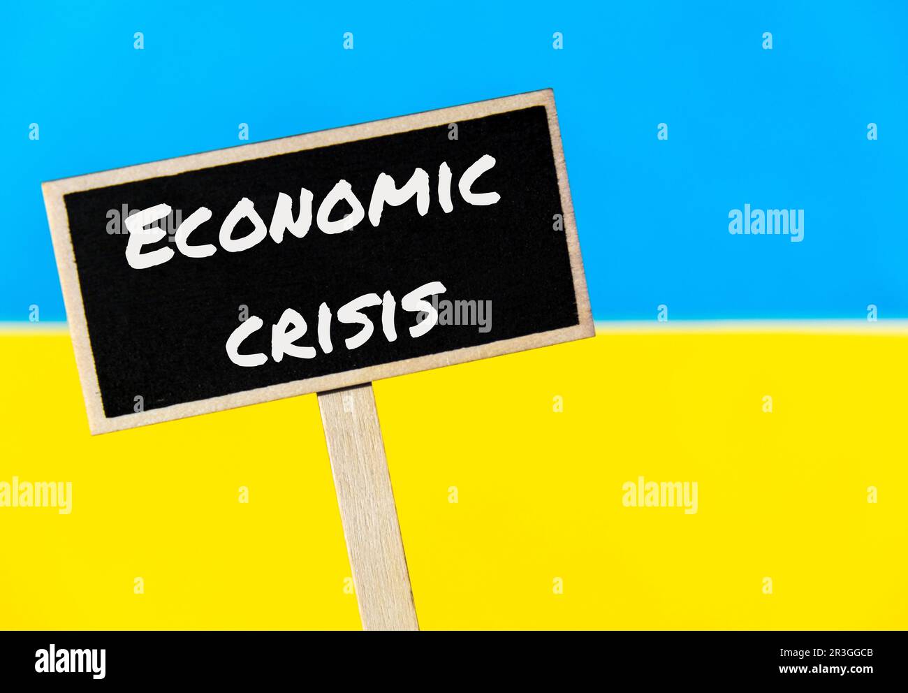 Segnale di etichetta di informazioni in legno con testo CRISI ECONOMICA contro messaggio di bandiera nazionale Ucraina. Fame globale, inflazione, alta Foto Stock
