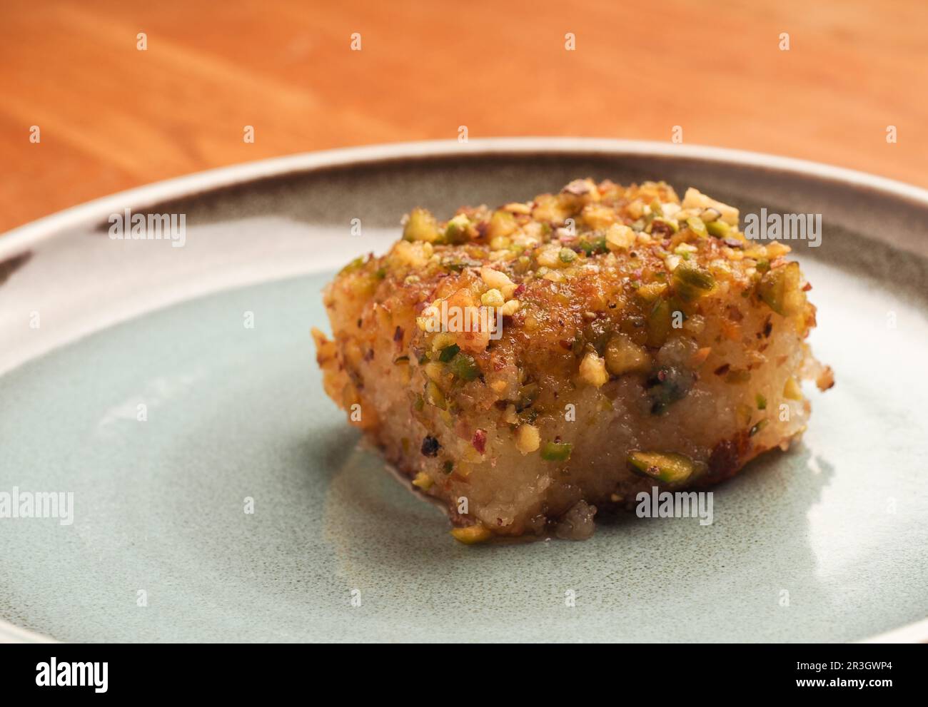 Torta di semola siriana con sciroppo di zucchero, gustoso Harisse su un piatto di ceramica blu, dessert siriano Foto Stock