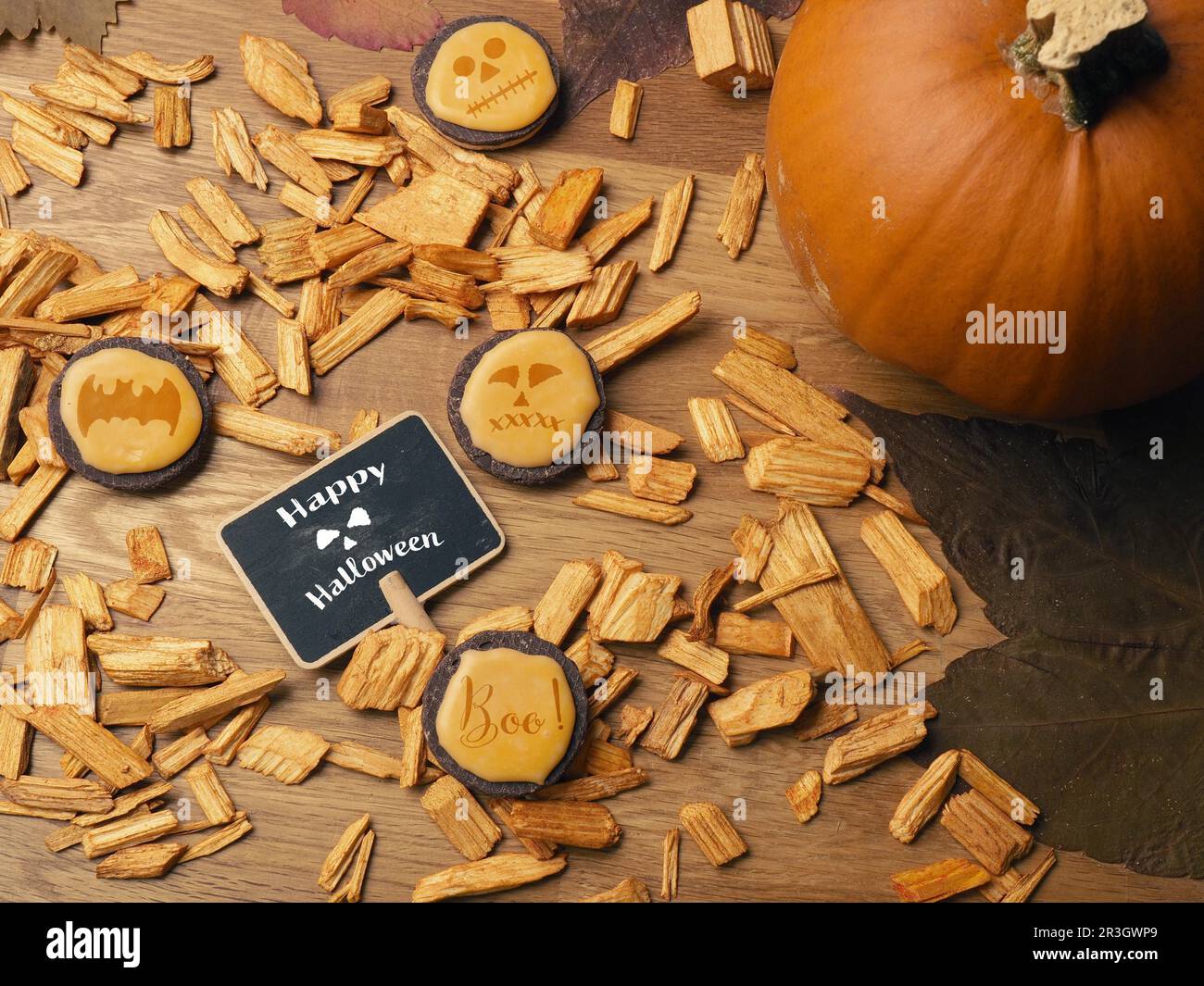 Halloween felice scritto su una piccola lavagna con biscotti e zucca su un tavolo di legno Foto Stock