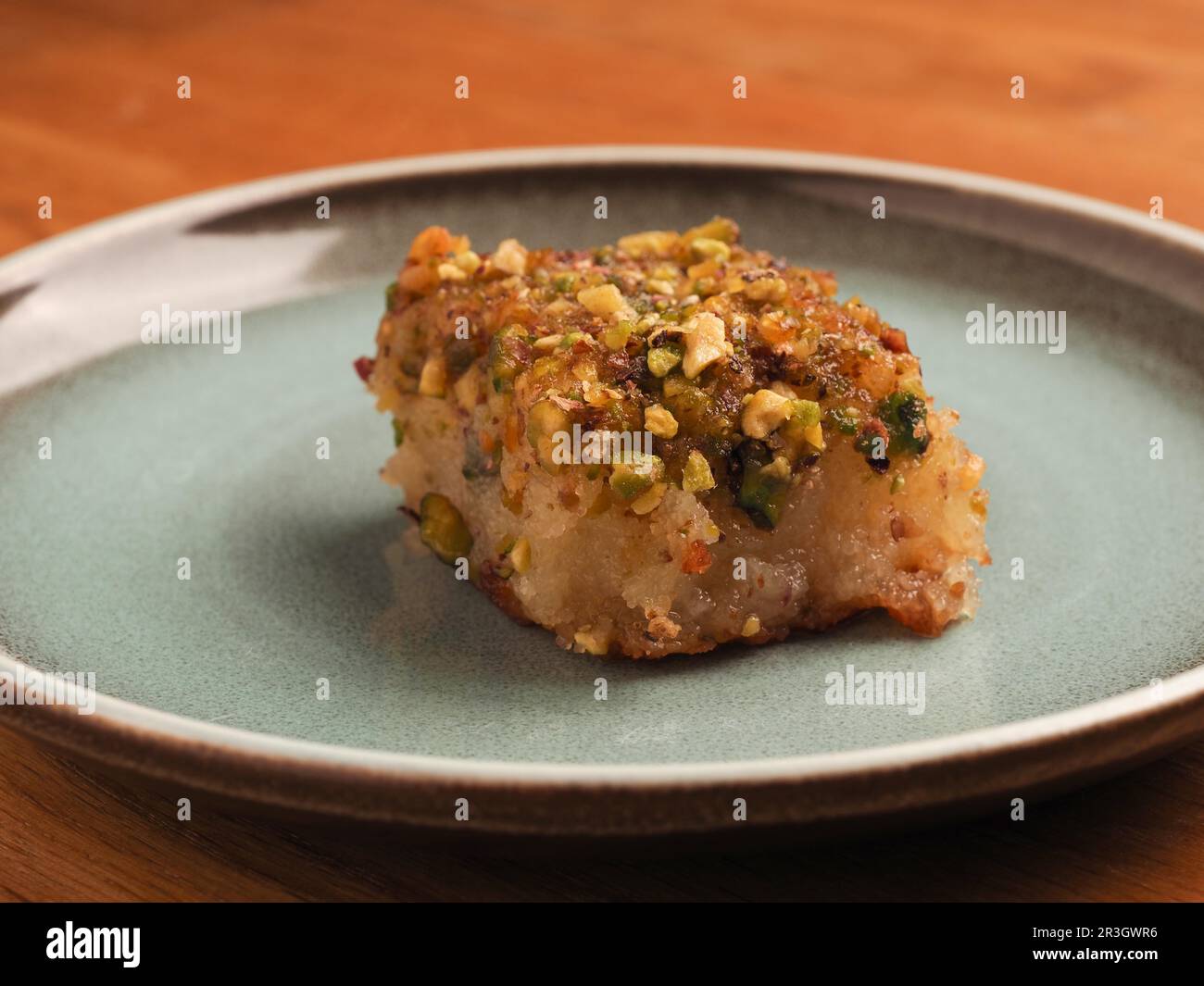 Torta di semola siriana con sciroppo di zucchero, gustoso Harisse su un piatto di ceramica blu, dessert siriano Foto Stock