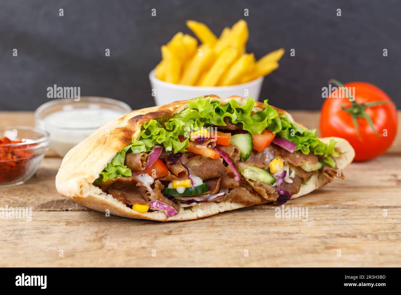 Doner kebab Doner kebap pasto fast food nel menu del pane pita con patatine fritte su tavola di legno Foto Stock