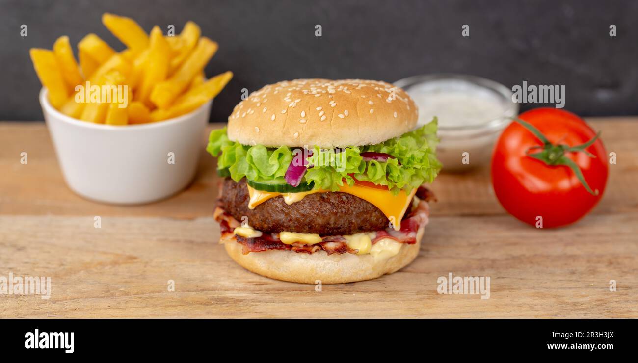 Hamburger cheeseburger menu fast food con patatine fritte su tavola panoramica di legno Foto Stock