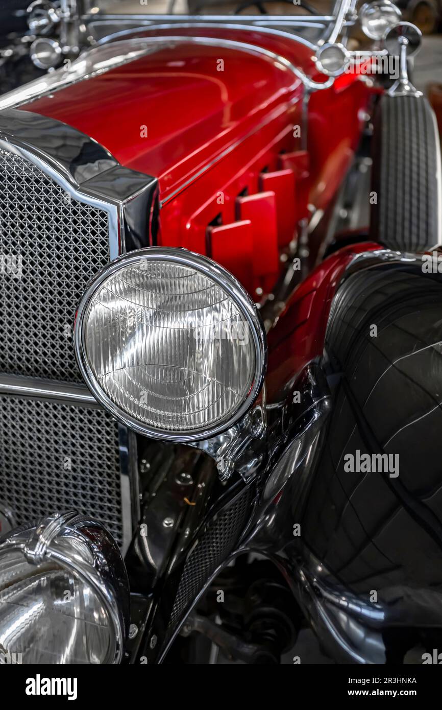 Frammento di un'auto retrò rossa e nera lucida con un design unico di un'elegante forma della griglia cromata di questa auto d'epoca e con fari rotondi Foto Stock