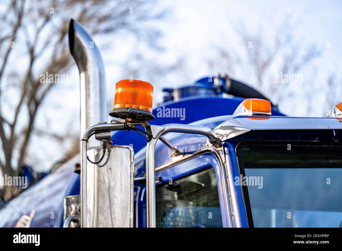 Day Cab standard industriale semirimorchio blu grandi carri con luce lampeggiante arancione sul tetto e semirimorchio serbatoio in piedi sulla stra provinciale della città Foto Stock