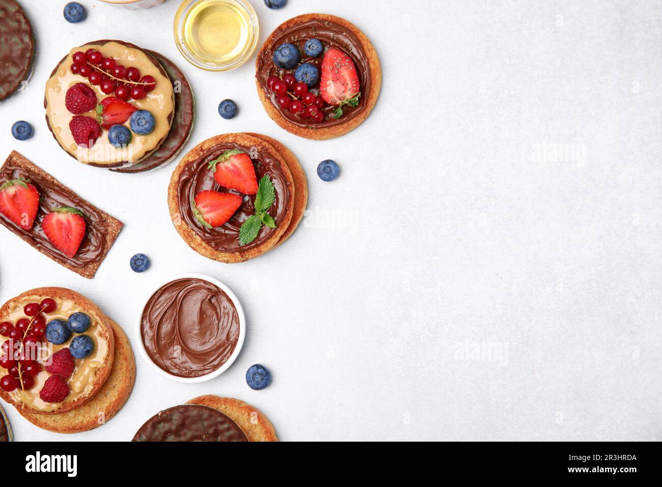 Crocchette di segale fresche, torte di riso croccanti e fette biscottate con diversi condimenti su tavolo grigio chiaro, piatto. Spazio per il testo Foto Stock