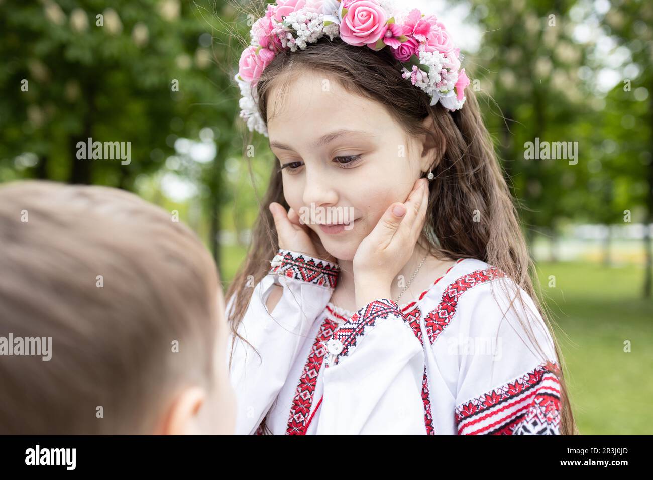 faccia della ragazza di 7 anni sta tenendo le mani del fratello più giovane. Entrambi i bambini sono vestiti in vestiti ucraini ricamati Foto Stock