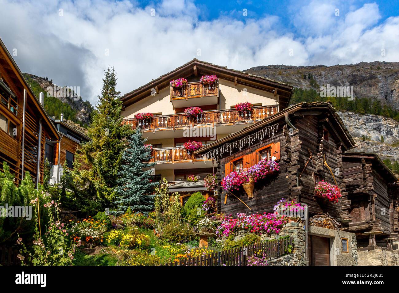 Tradizionale chalet alpino in legno con fiori di geranio sulla finestra in estate, Zermatt villaggio alpino, Svizzera, Alpi svizzere Foto Stock