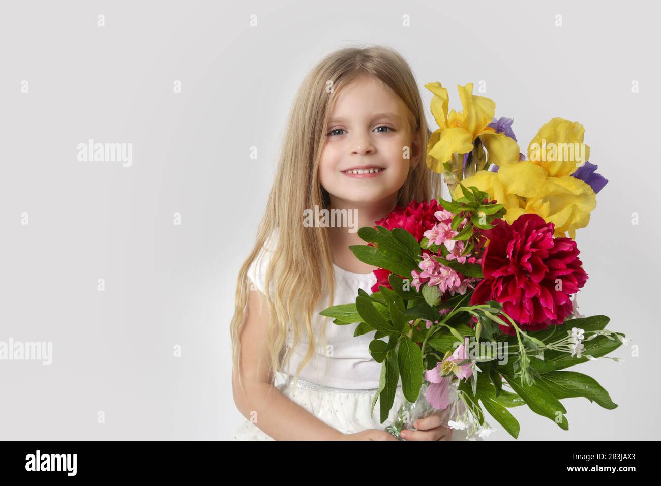 Ritratto in studio di una bellissima bambina che regge un grande bouquet colorato di vari fiori. Foto Stock