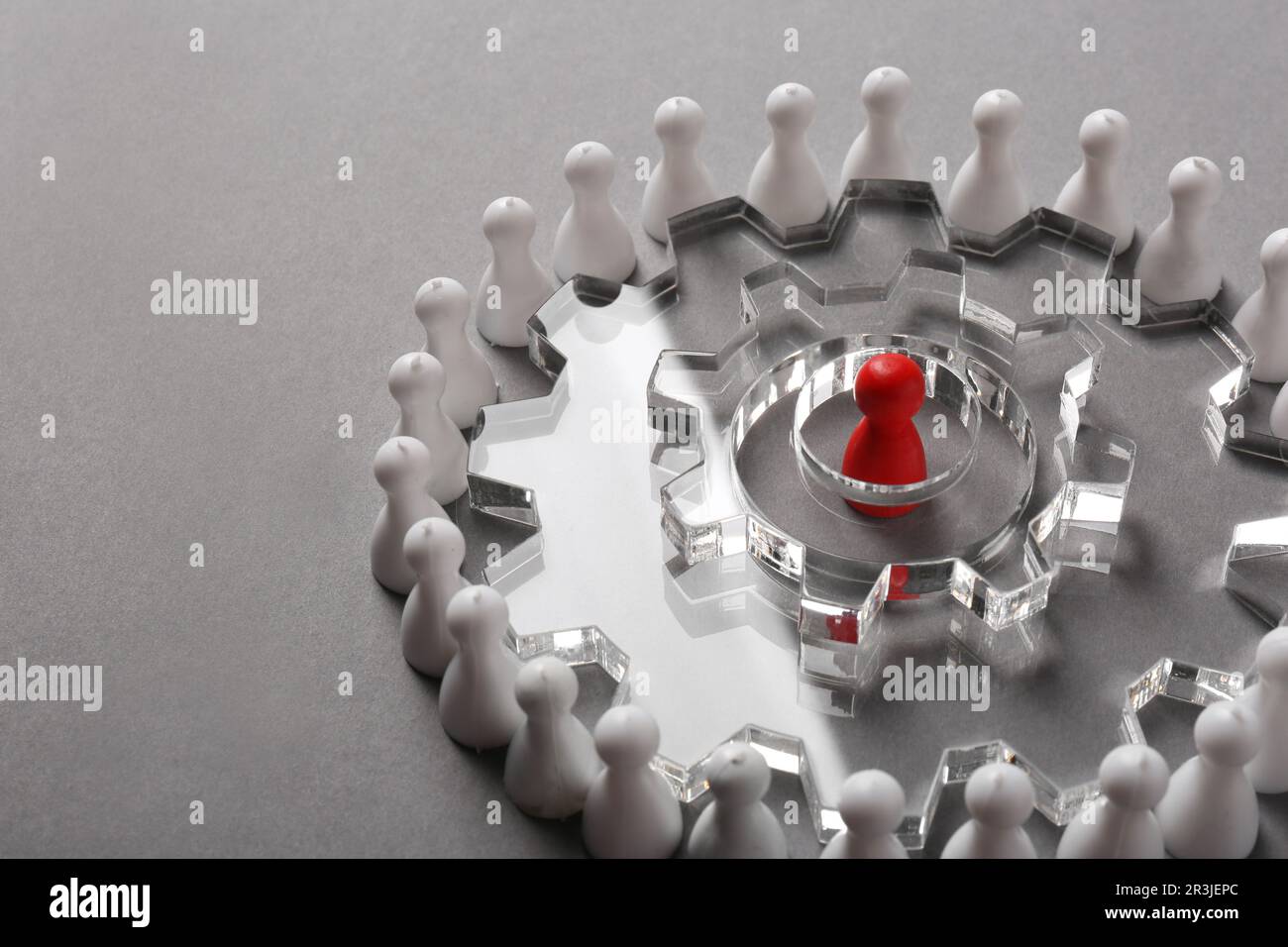 Processo di selezione dei dipendenti. Composizione con ruote dentate, pedina rossa come recruiter e bianca come candidati su sfondo grigio chiaro. Spazio per il testo Foto Stock