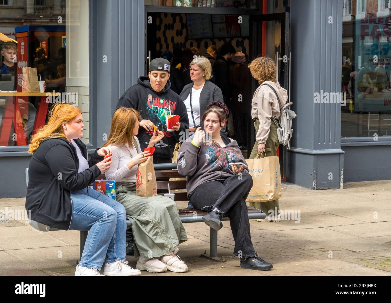 I giovani si sedettero al tavolo mangiando i piatti da asporto del Wendy's Burger Bar dietro, High Street Lincoln City, Lincolnshire, Inghilterra, Regno Unito Foto Stock