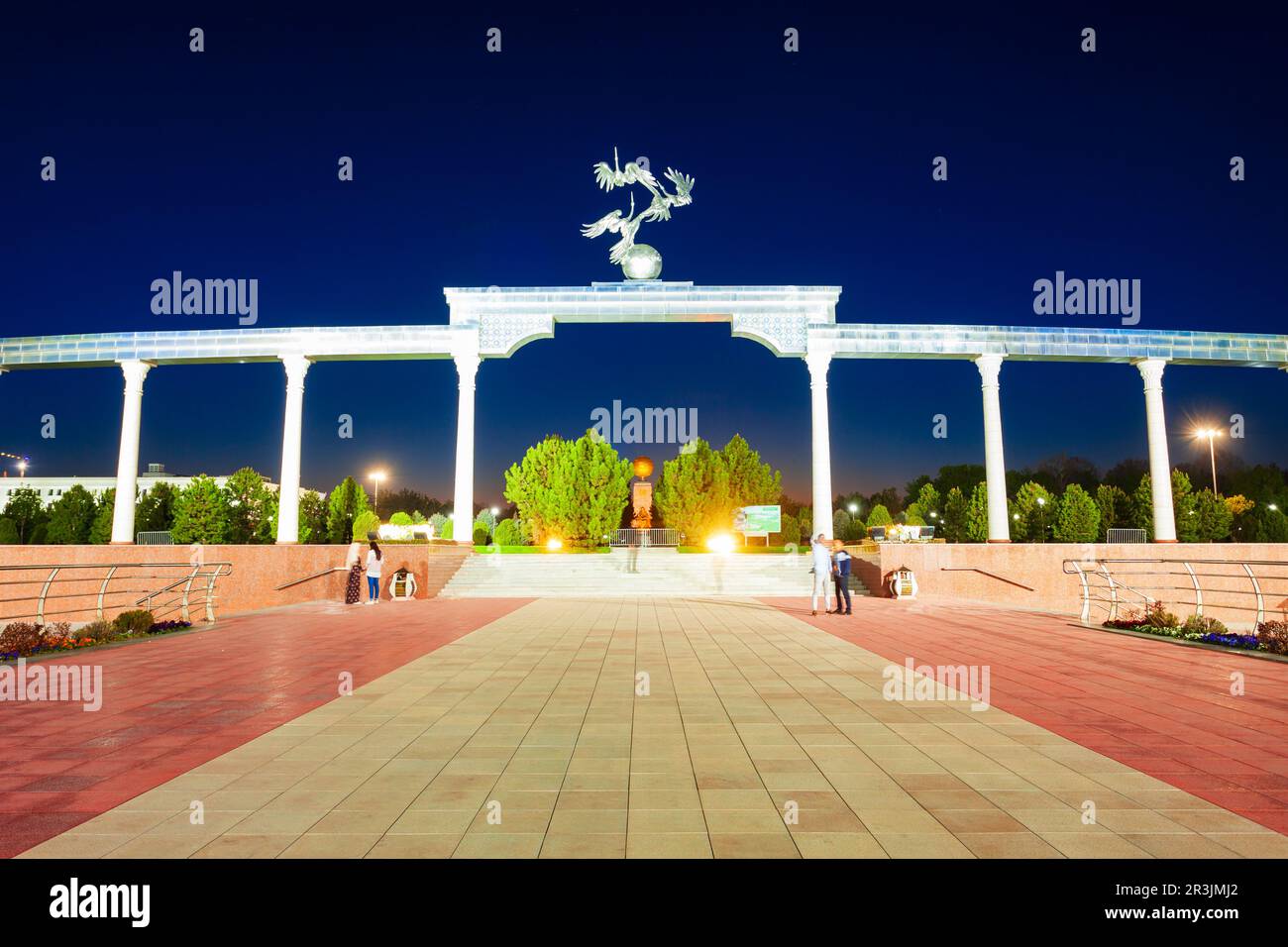 Cicogne che volano sul globo nell'Arco di bene e di Nobile Ezgulik di aspirazioni in Piazza Indipendenza, Tashkent città in Uzbekistan di notte Foto Stock