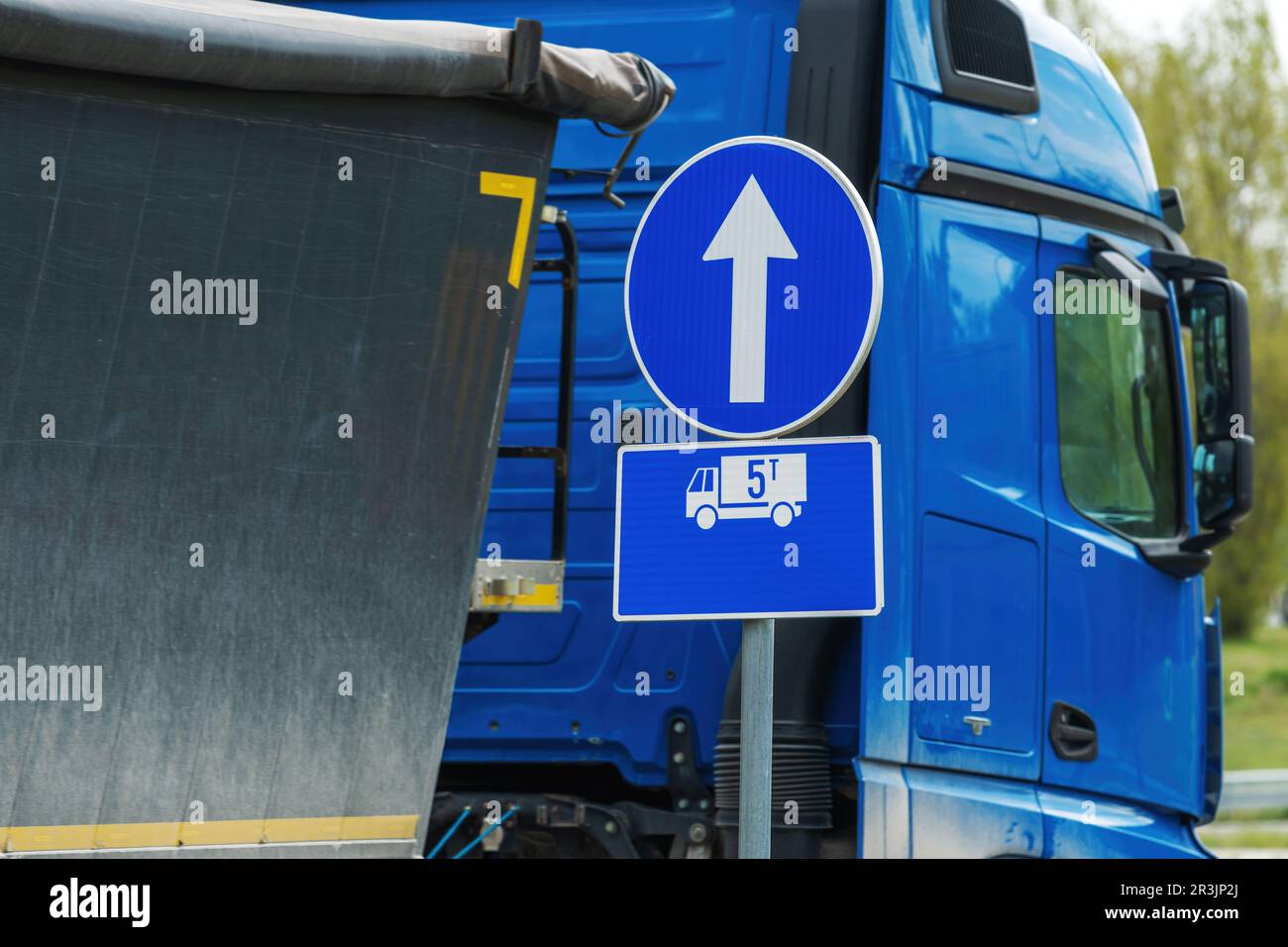 Segnale di direzione obbligatorio per veicoli pesanti di peso superiore a cinque tonnellate, segnaletica circolare blu europea con freccia bianca, messa a fuoco selettiva Foto Stock