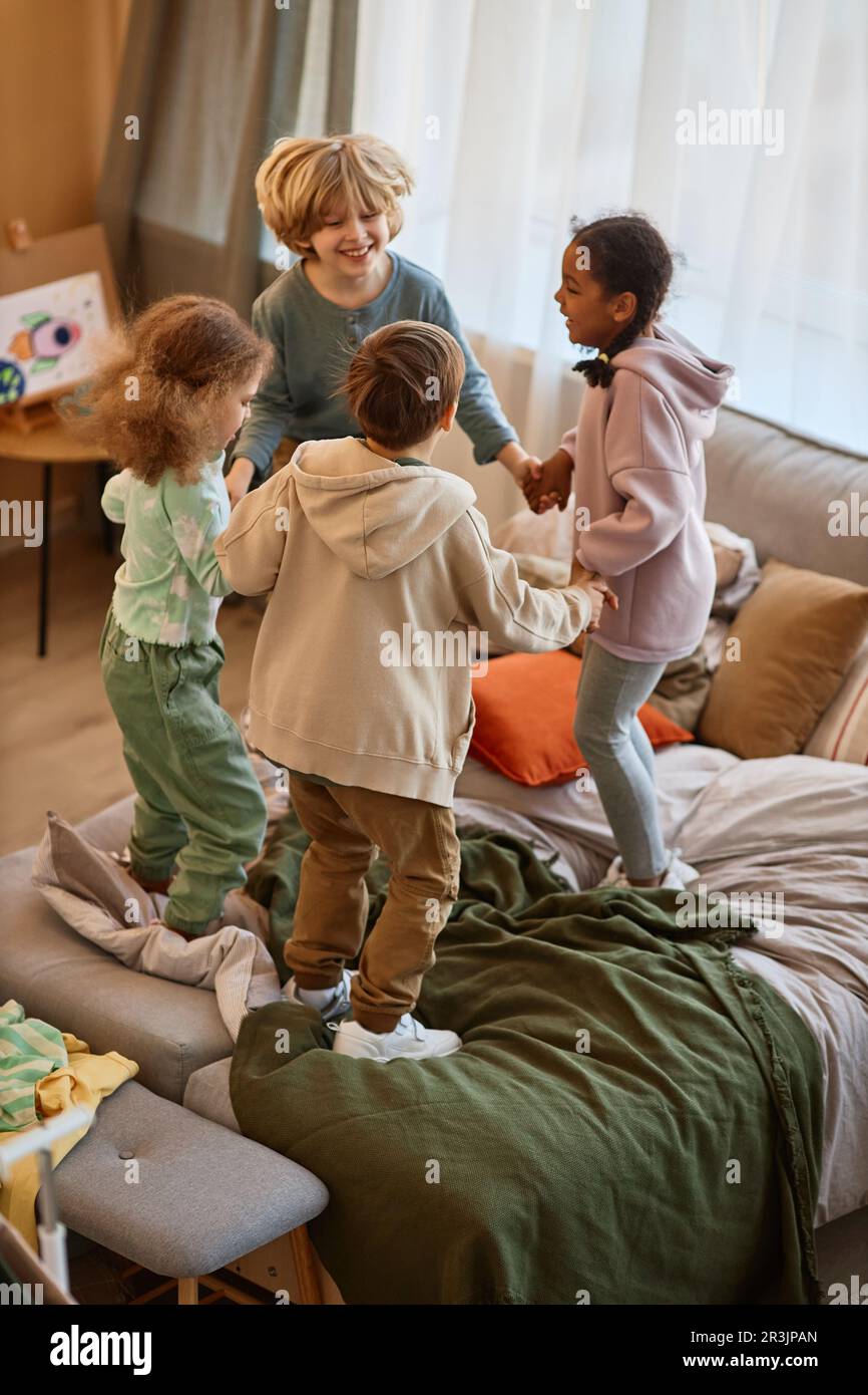 Gruppo di bambini che saltano sul letto insieme e tenendo le mani Foto Stock