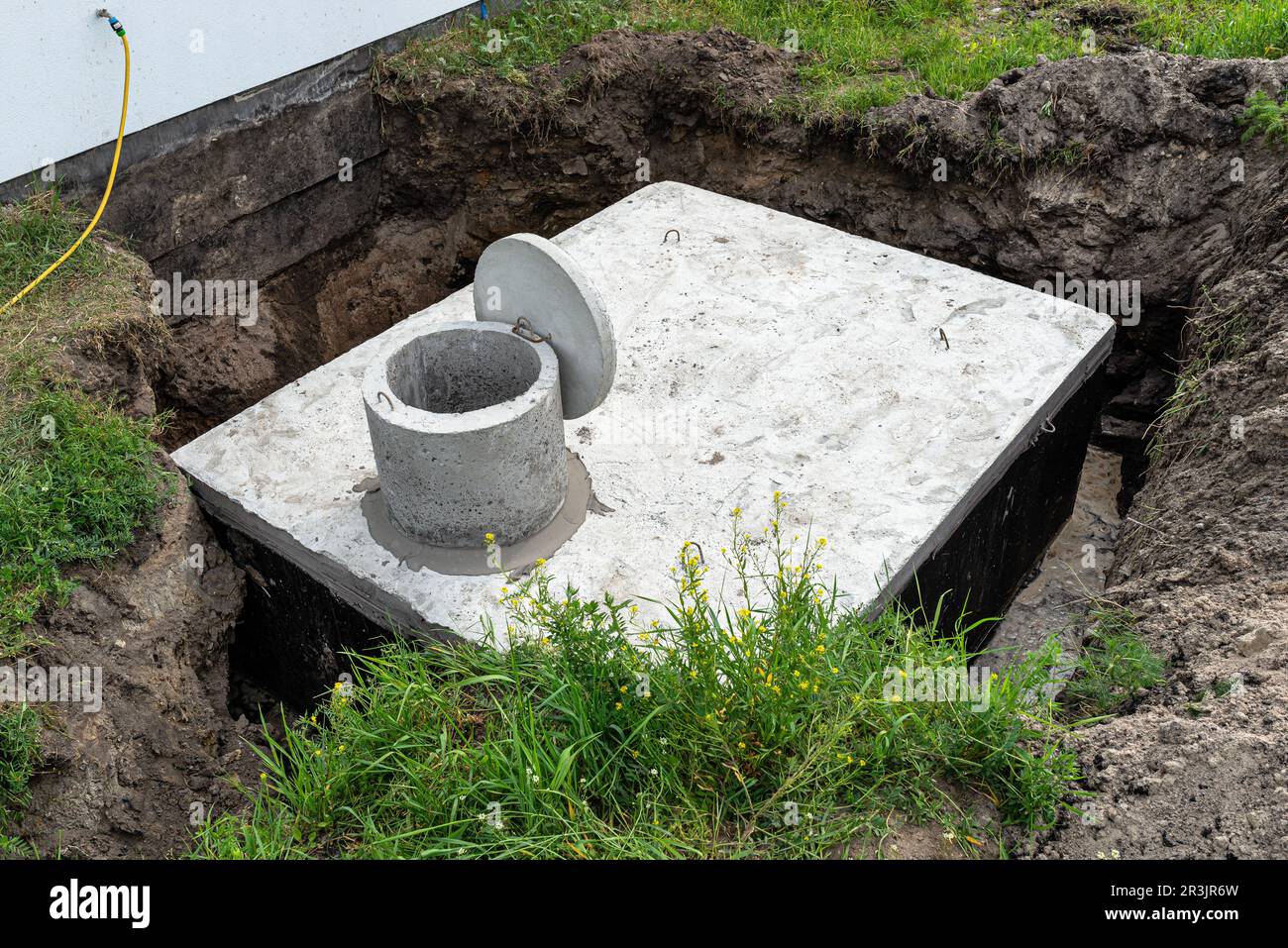 Serbatoio settico in cemento con una capacità di 10 metri cubi posto nel giardino dalla casa, acqua visibile sotto. Foto Stock