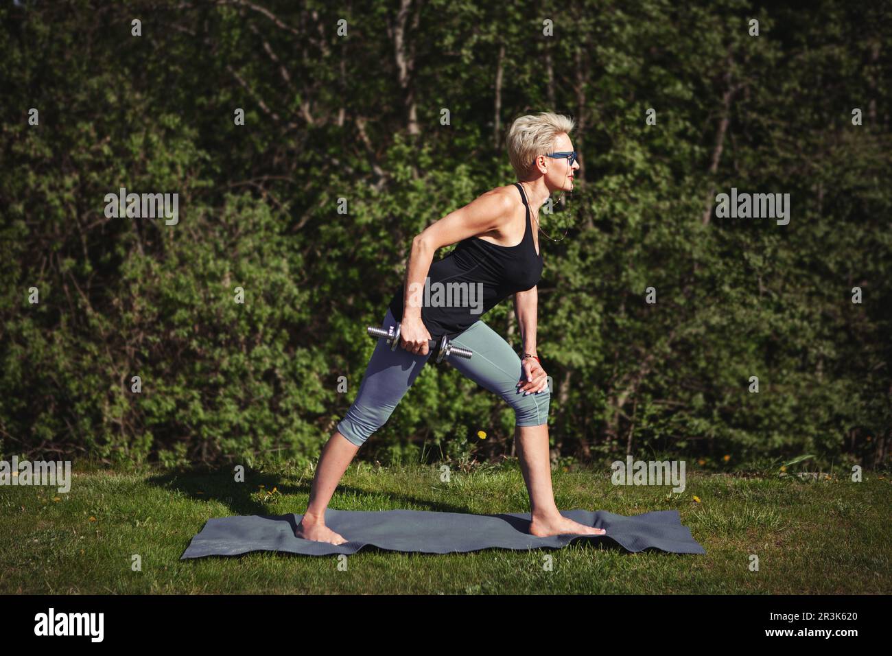 La donna anziana ama allenarsi, allenarsi con il manubrio, allenarsi in mezzo alla natura, dedicarsi a uno stile di vita sano e rimanere attiva. OU Foto Stock