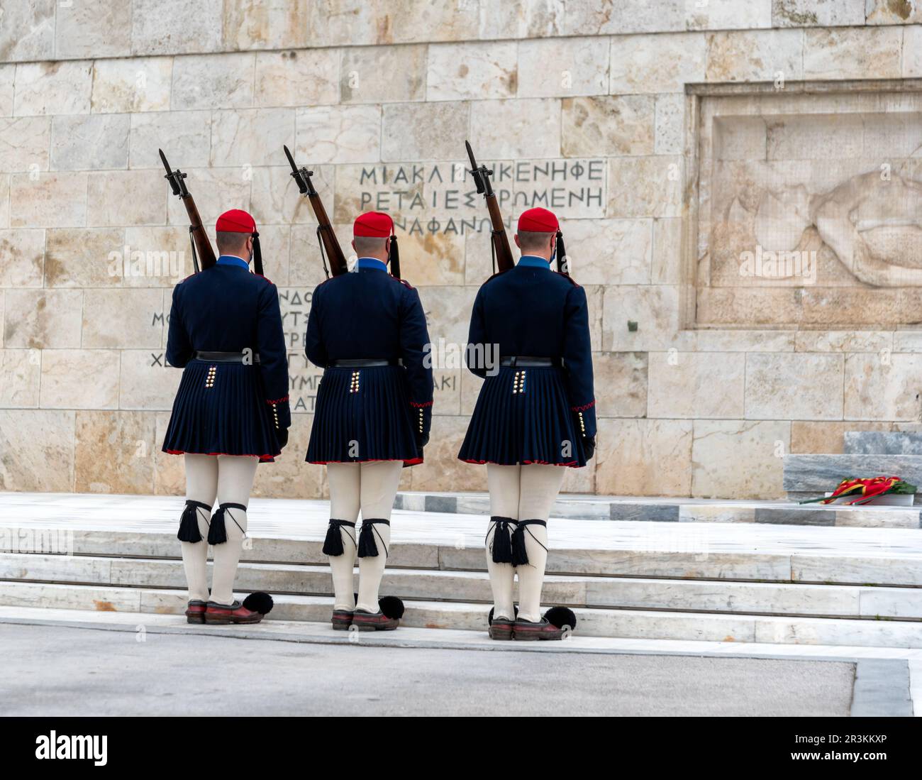 Testo sul muro e un letto rimane vuoto per l'ignoto in greco e greco Evzone soldati in costumi tradizionali Foto Stock