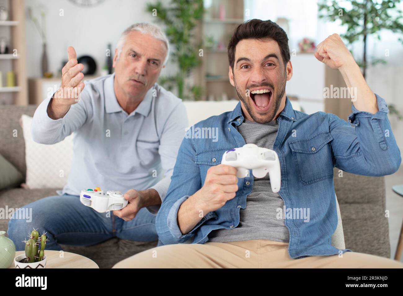rovesciare l'uomo anziano perdendo il videogioco al suo figlio maturo Foto Stock