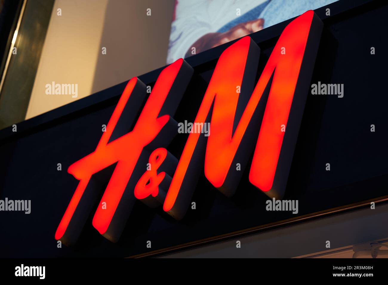 Pubblicità illuminata del rivenditore tessile svedese H&M, Hennes & Mauritz, a Berlino Foto Stock