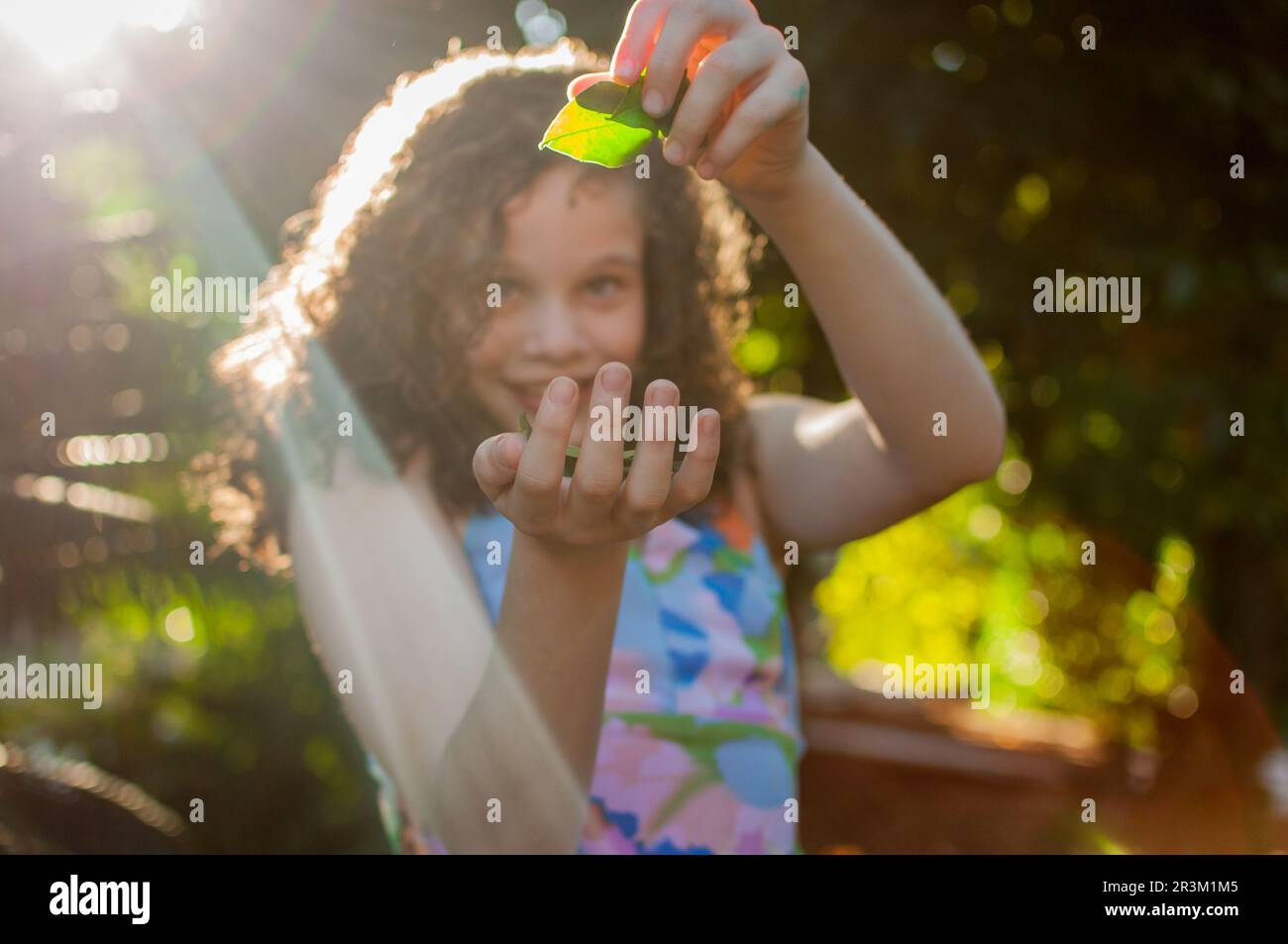Ritratto di bella ragazza capelli ricci che gioca con una foglia Foto Stock