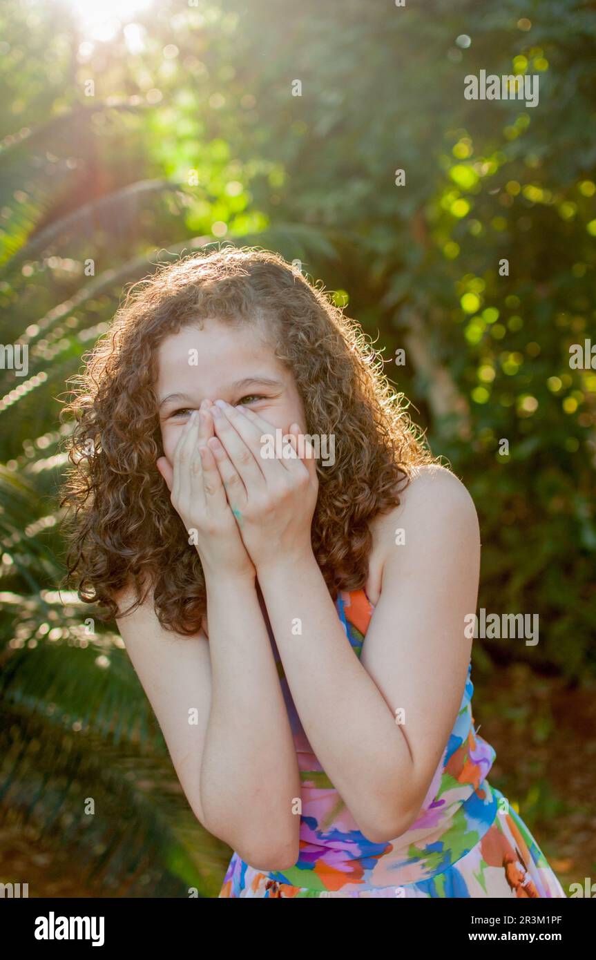Ragazza che copre il sorriso con le mani Foto Stock