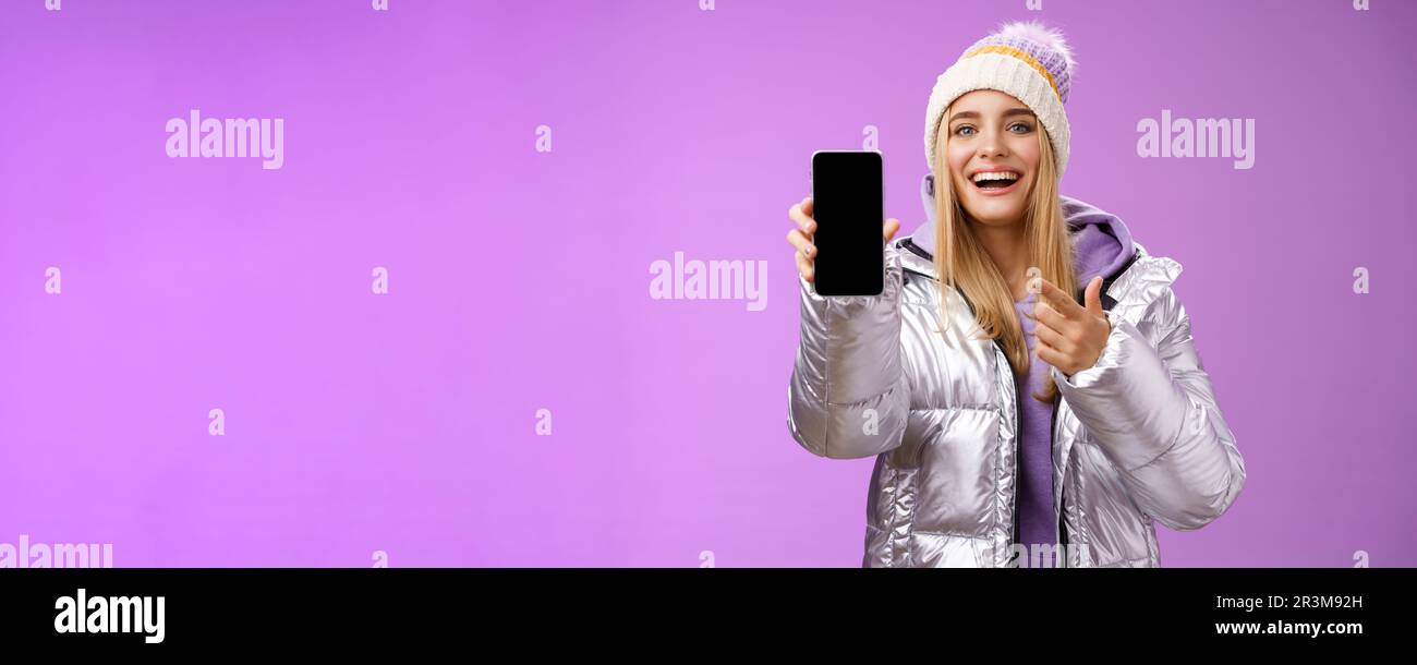 Soddisfatto divertito buon-sguardo bionda ragazza suggerisce lo schermo dello smartphone di Take Look sorridente felice di indicare il telefono cellulare felice ta Foto Stock