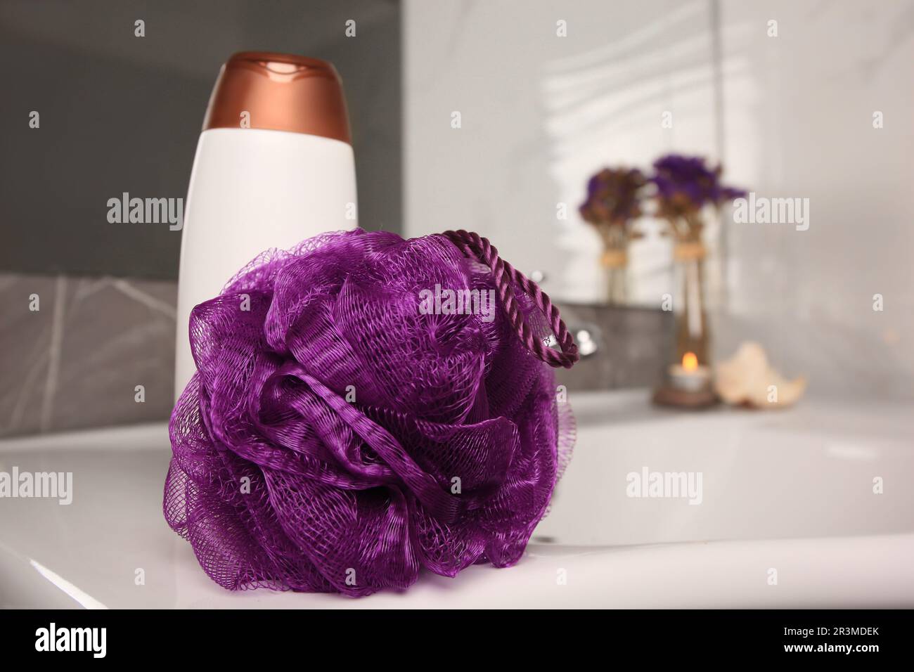 Soffio doccia viola e bottiglia di gel per il lavaggio del corpo sul lavandino in bagno, spazio per il testo Foto Stock