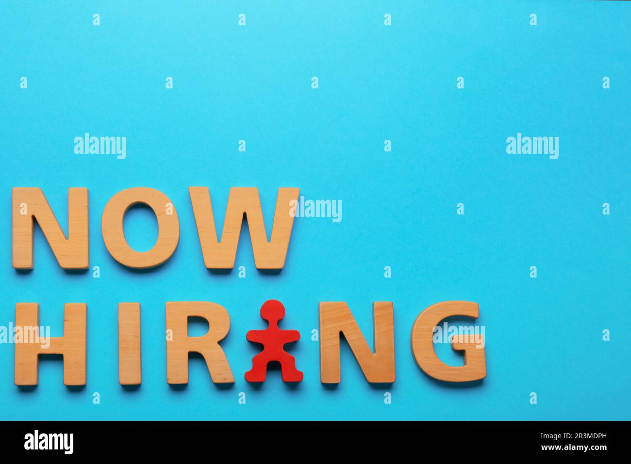 Processo di reclutamento. Frase ora assunzione fatta di lettere di legno e figura umana rossa su sfondo azzurro, piatto Foto Stock