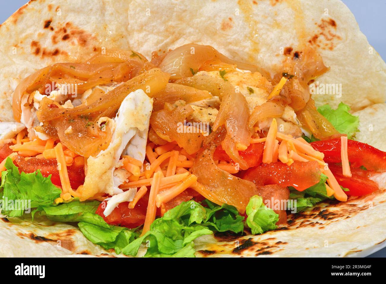 Pesce con cipolle e insalata in una tortilla. Foto Stock