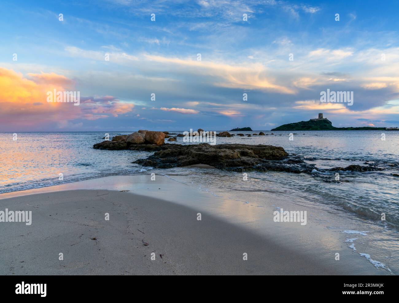 Vista panoramica di un colorato tramonto sulla spiaggia di Nora in Sardegna con la Torre Coltellazzo sullo sfondo Foto Stock