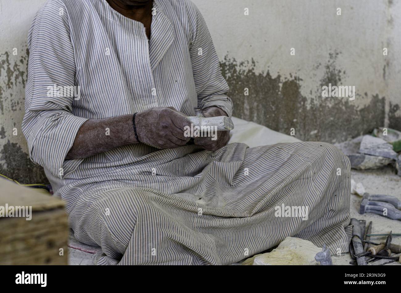 Mani di uno scultore egiziano maschio mentre lavora con un alabastro di pietra Foto Stock