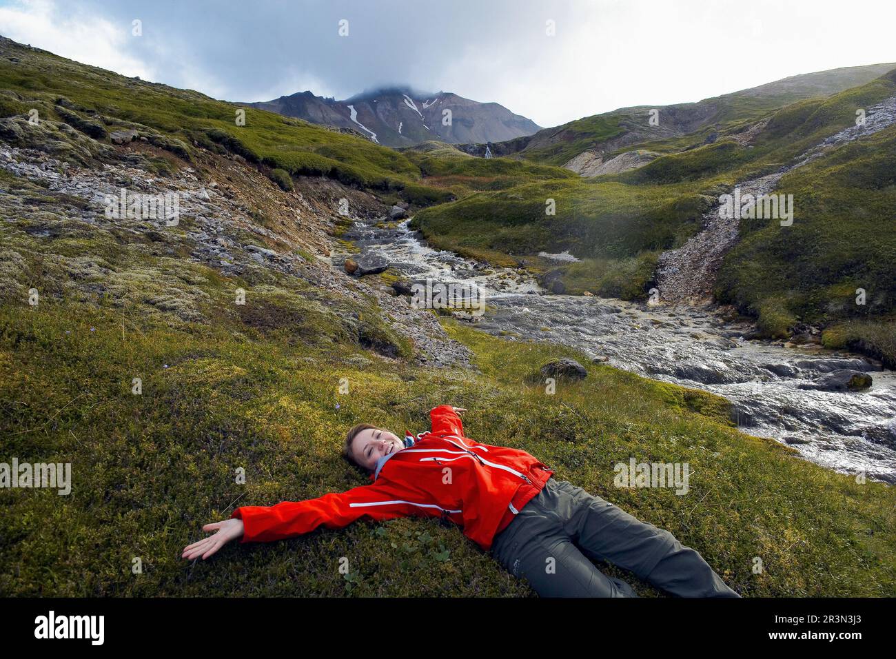 Donna rilassante che posa su erba in , Islanda orientale, Islanda Foto Stock