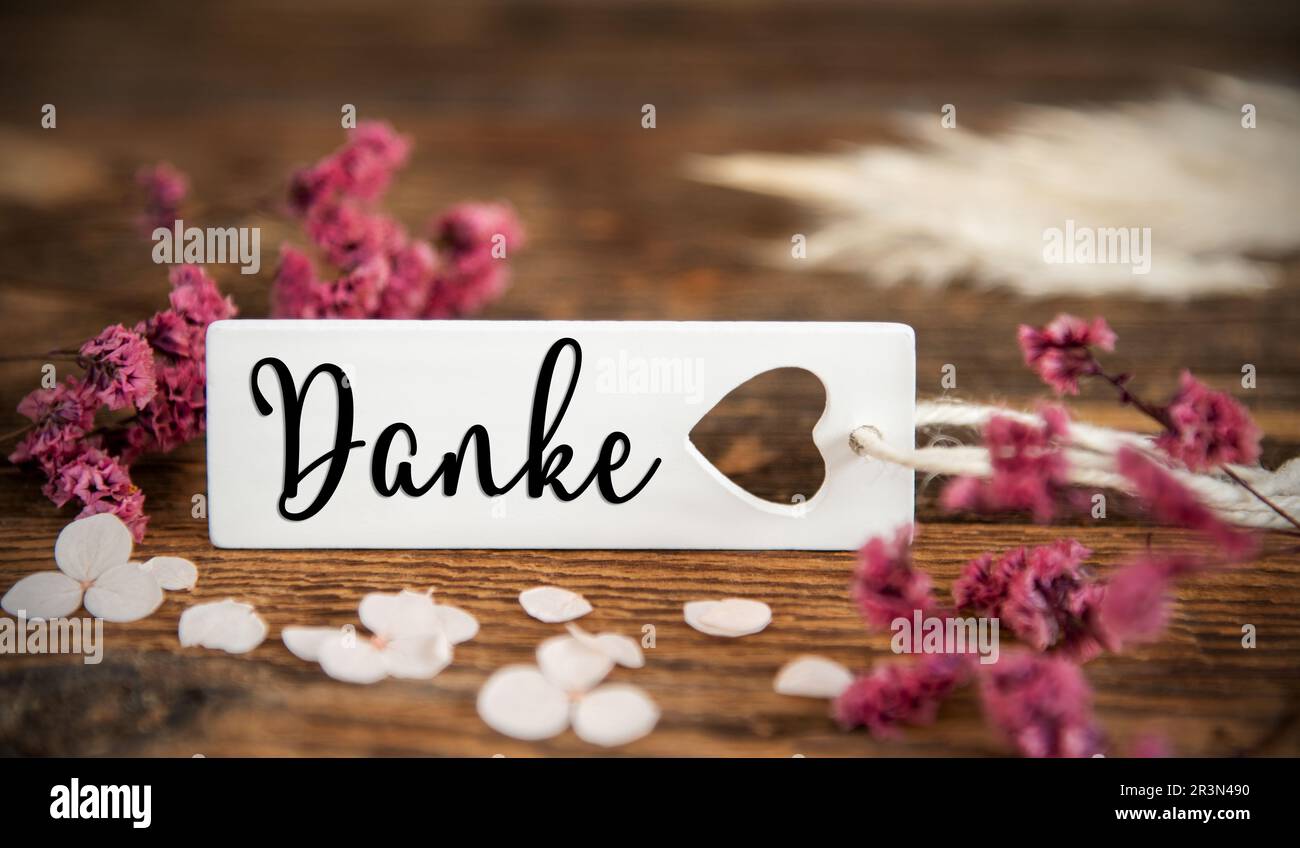 Sfondo naturale con fiori viola ed etichetta con la parola tedesca Danke, significa grazie in inglese, estate o autunno decorazione Foto Stock