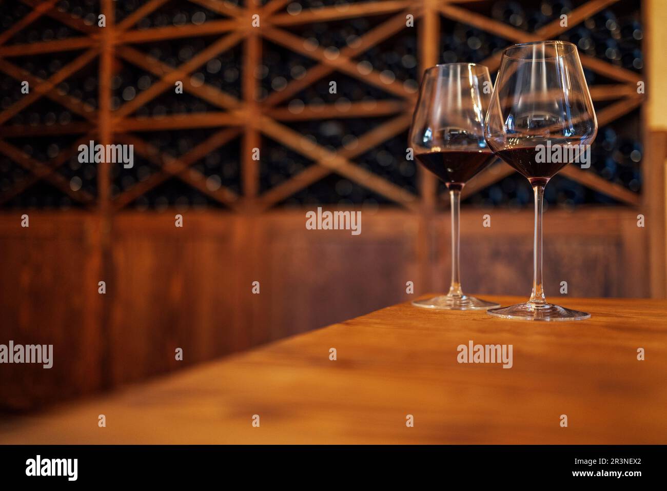 Bottiglie di vino su una mensola di legno. Wine bar. Due bicchieri con vino rosso su fondo in legno Foto Stock