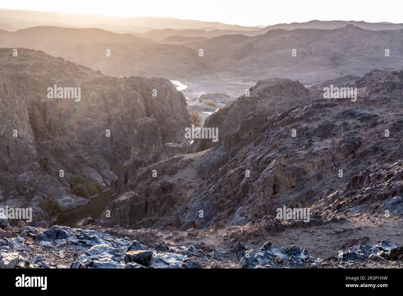 Splendida vista sulle montagne rocciose nere e rosse con un fiume sul fondo Foto Stock