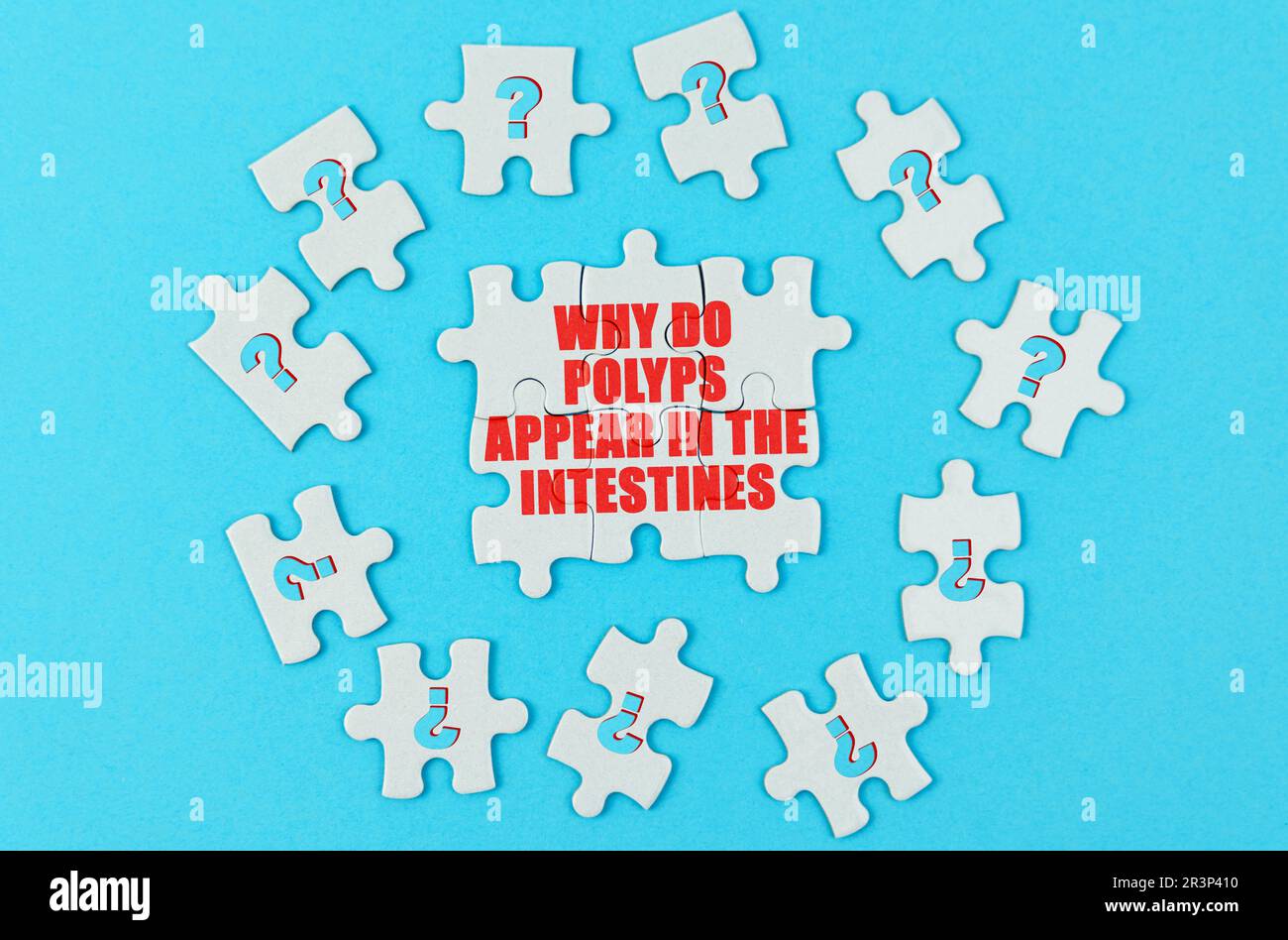 Concetto medico. Su una superficie blu sono i puzzle con un punto interrogativo, al centro con l'iscrizione - perché i polipi appaiono negli intestini Foto Stock