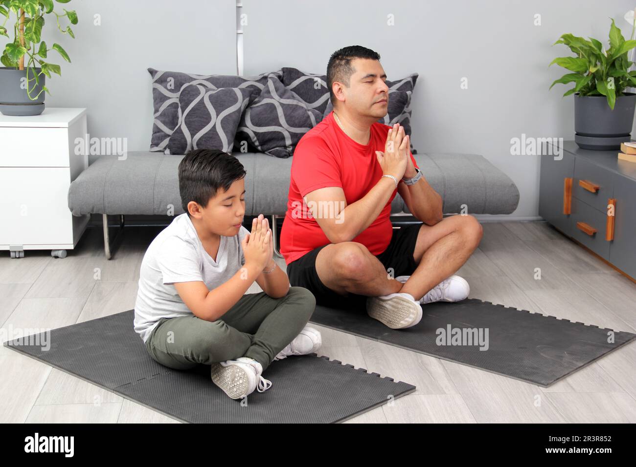 Il padre e il figlio di Latino praticano lo yoga, una disciplina spirituale, fisica e mentale tradizionale nella calma e nel rilassamento per migliorare l'autostima Foto Stock