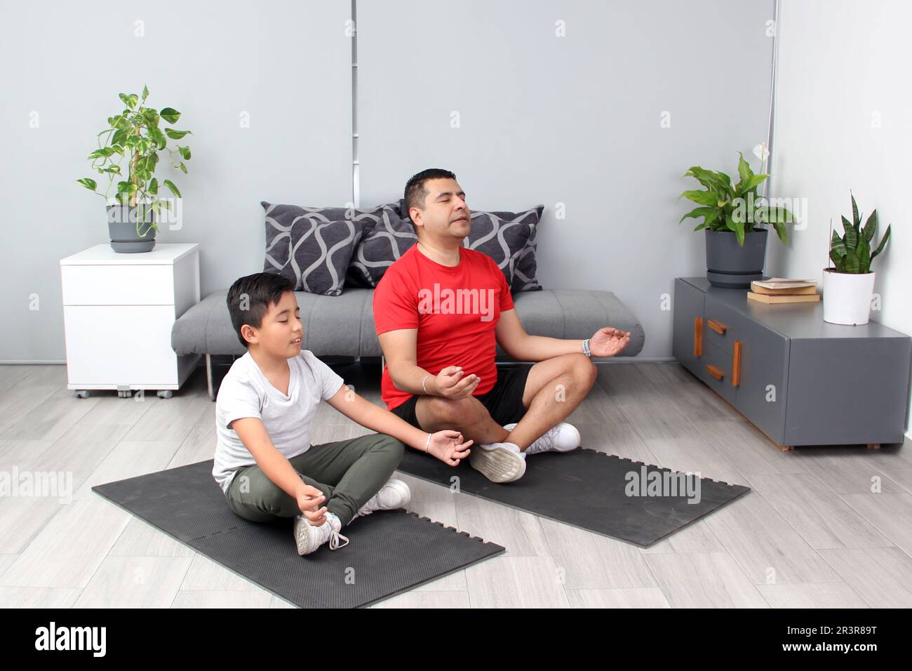 Il padre e il figlio di Latino praticano lo yoga, una disciplina spirituale, fisica e mentale tradizionale nella calma e nel rilassamento per migliorare l'autostima Foto Stock