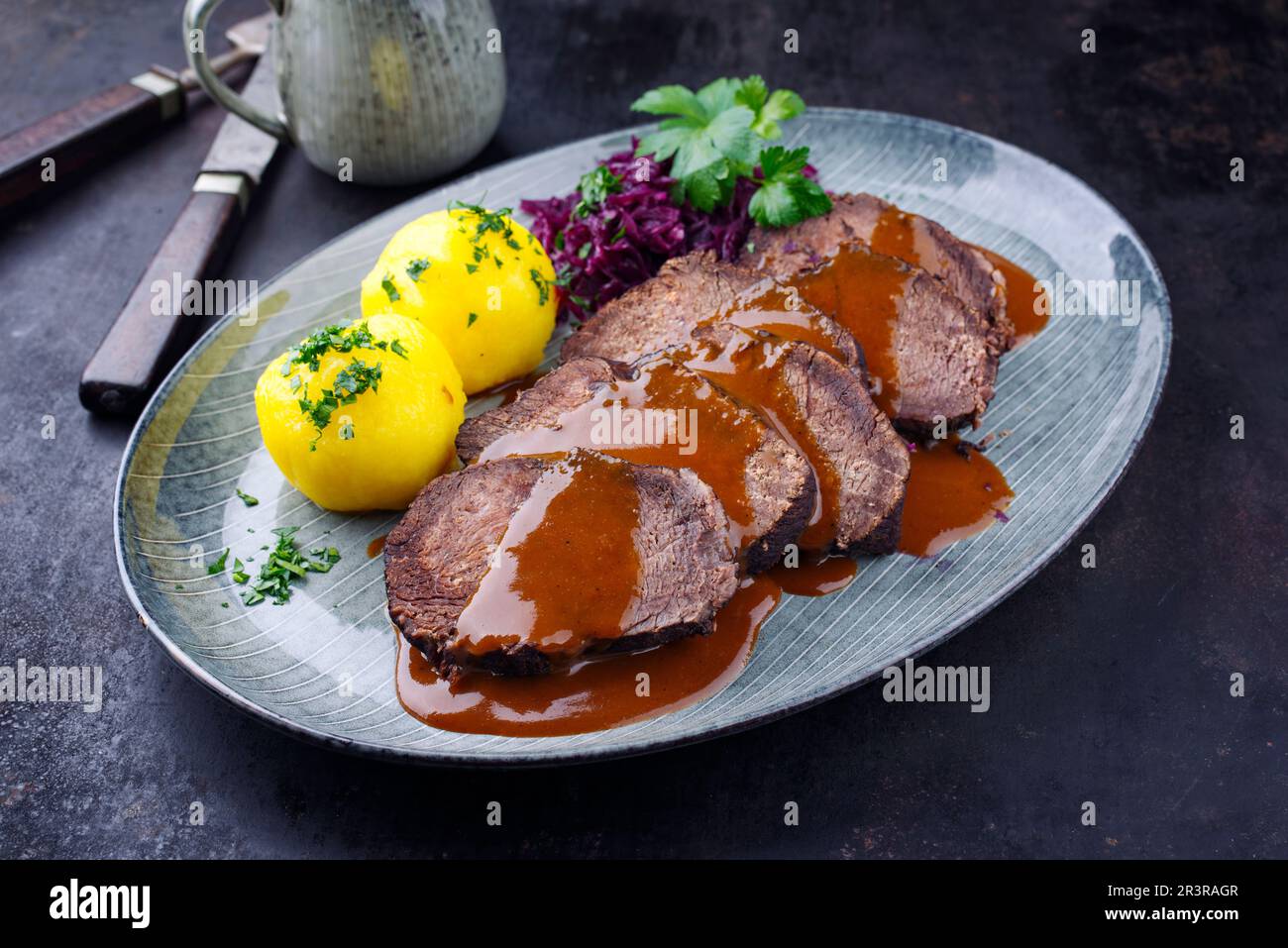 Tradizionale Sauerbraten tedesco marinato brasato di manzo con kraut blu e gnocchi di patate in salsa piccante di birra scura servito Foto Stock