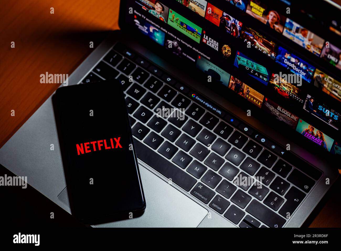 ITALIA - 24 maggio 2023: Pagina iniziale di Netflix sullo schermo di un computer portatile Mac e logo con lettere sullo schermo dello smartphone. Netflix è uno streaming video online Foto Stock