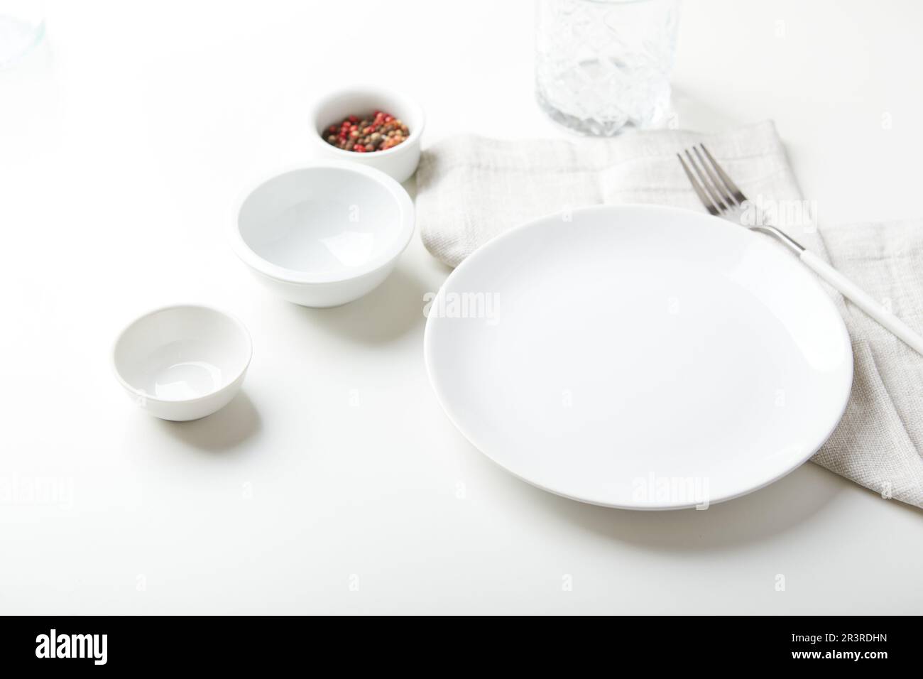 Piatto bianco vuoto con forchetta e ciotole su sfondo chiaro Foto Stock