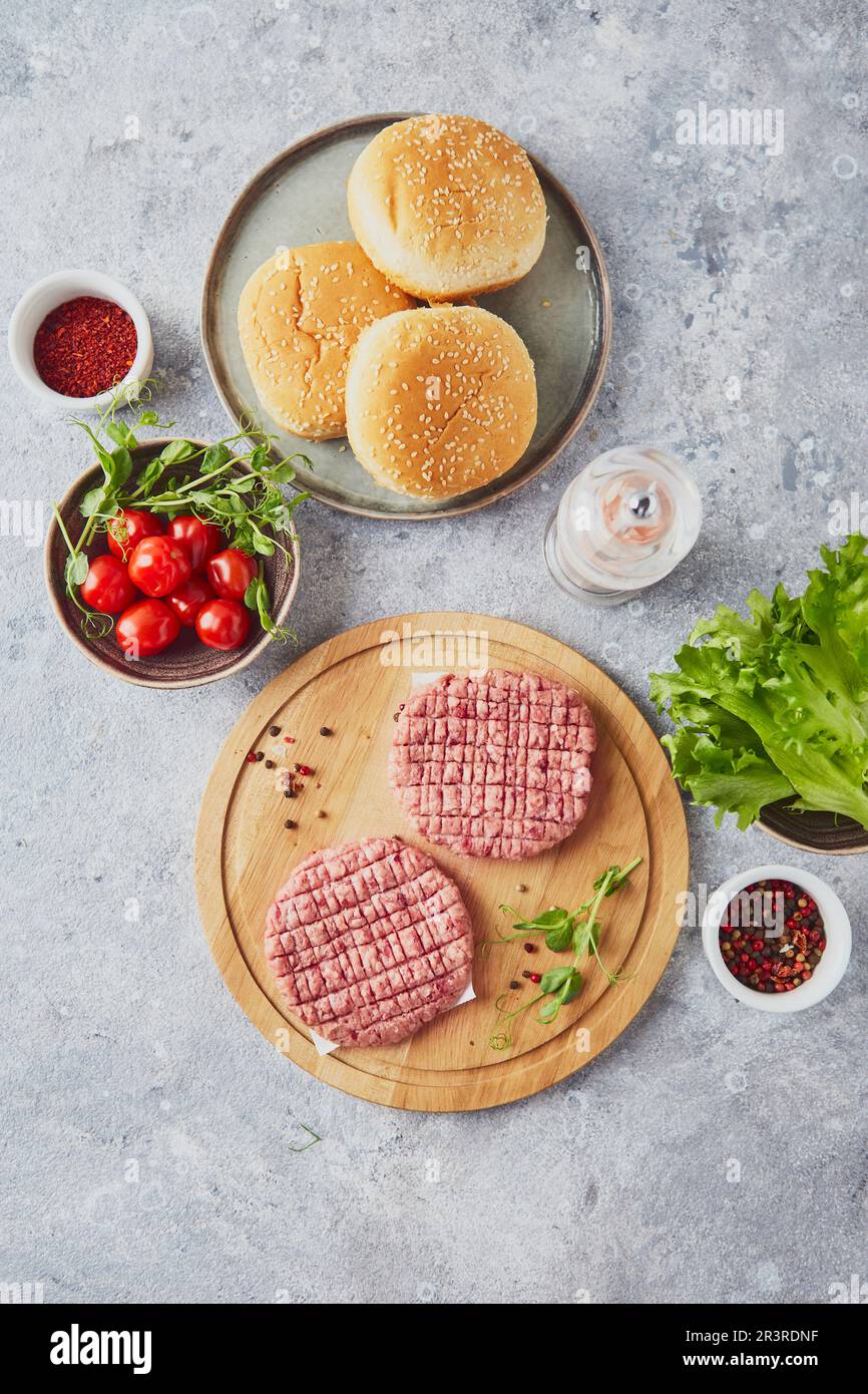 Cotolette di bistecca di vitello crudo al Burger su tagliere in legno Foto Stock